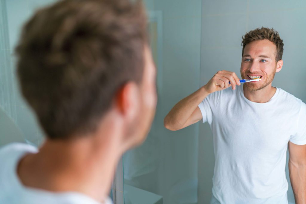 man brushing his teeth after his nashville teeth whitening treatment at 21st century dentistry
